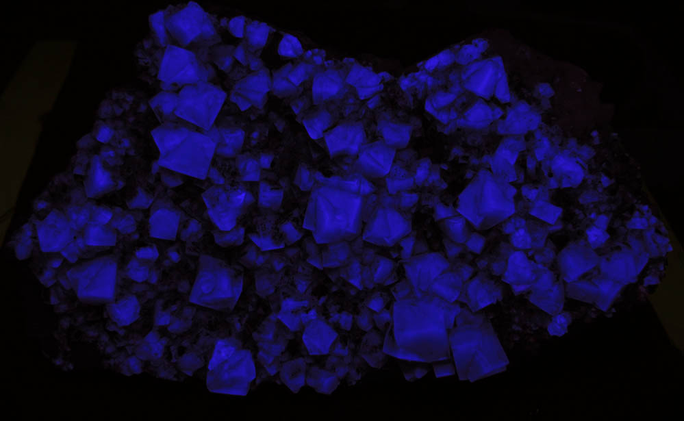 Photo below under shortwave ultraviolet illumination of Fluorite (twinned crystals) on Quartz with Galena from Blackdene Mine, Ireshopeburn, Weardale, County Durham, England Fluorite (twinned crystals) on Quartz with Galena from Blackdene Mine, Ireshopeburn, Weardale, County Durham, England